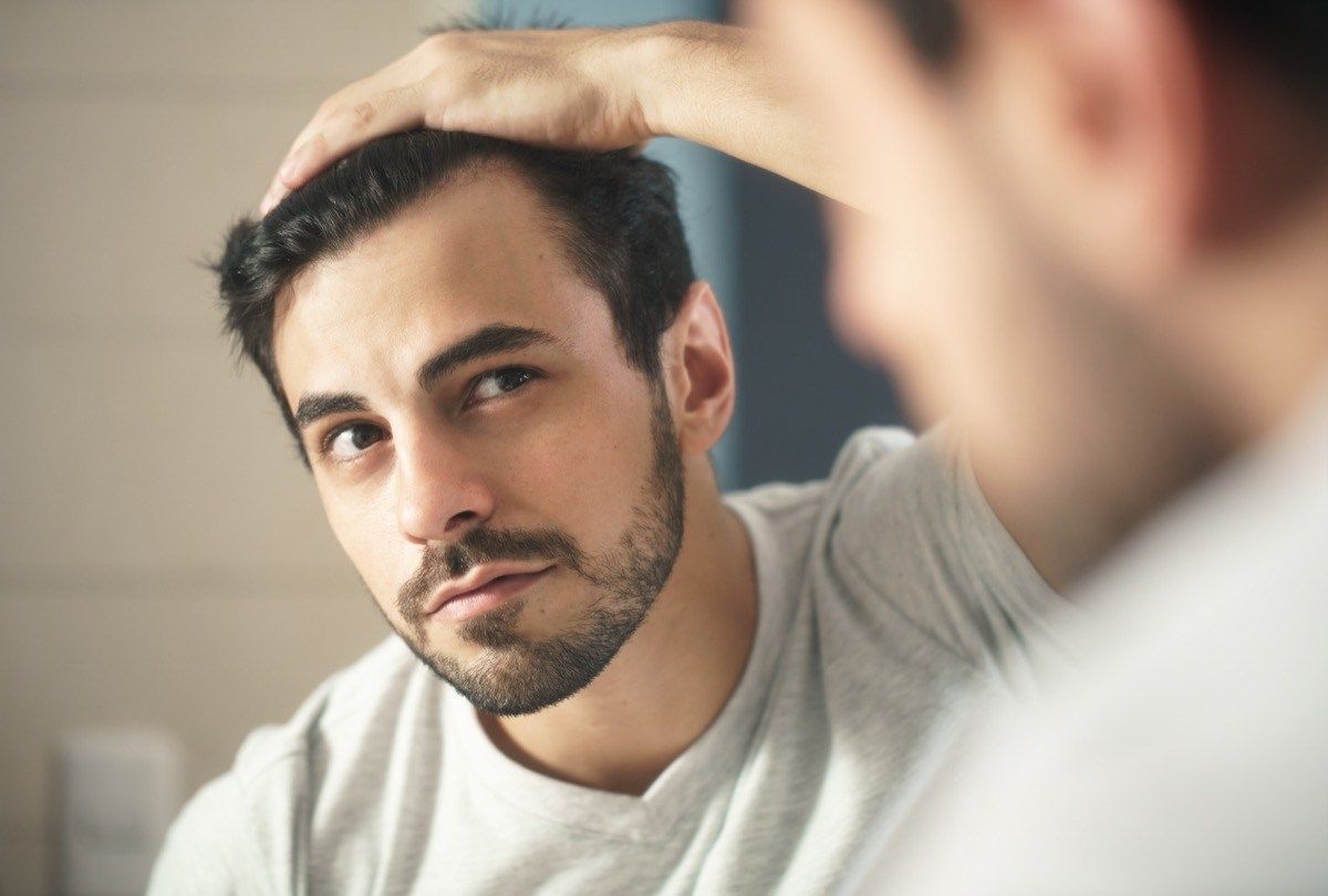 muž sa pozerá do zrkadiel na sivé vlasy