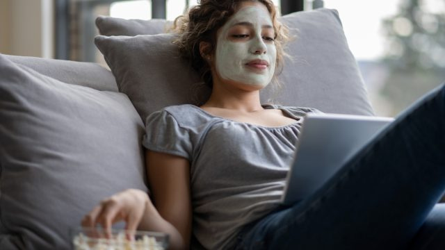   Жена, релаксираща у дома с маска на лицето, яде пуканки, докато снимка id1242508945