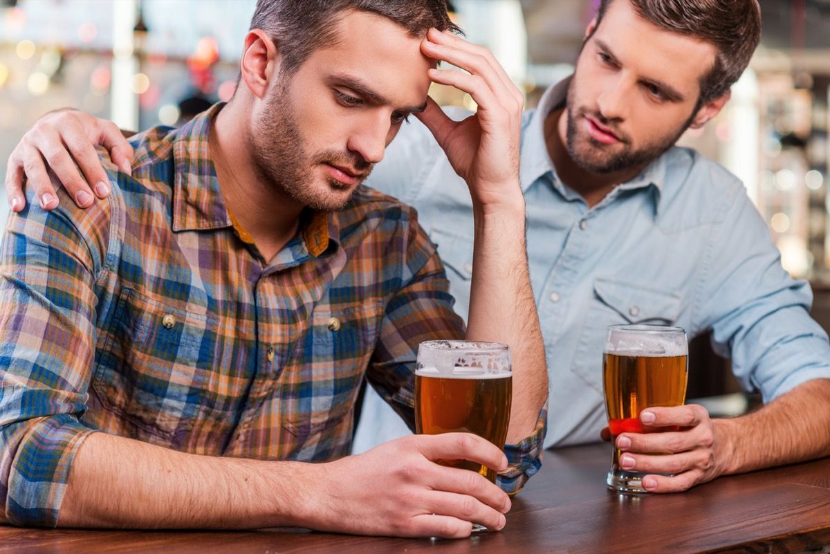 bijeli čovjek stavivši ruku oko drugog bijelca dok oni piju piva