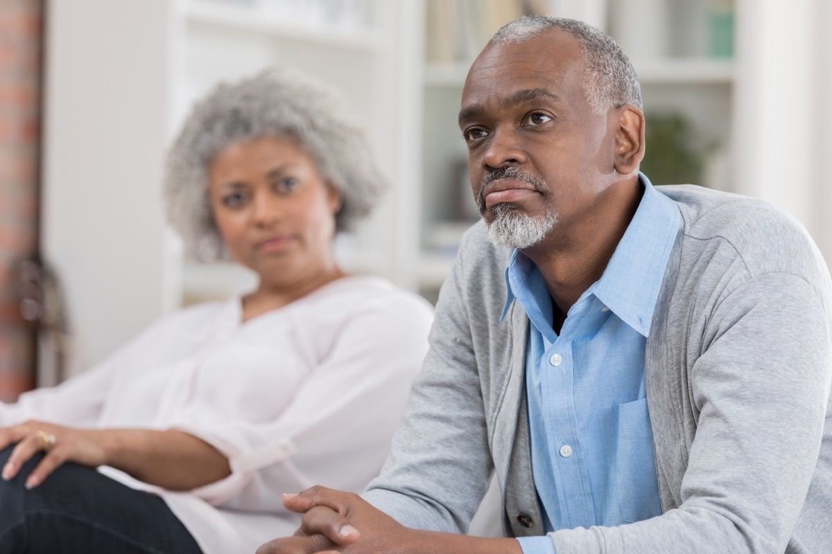 stariji crnac koji sjedi naprijed na kauču dok starija crnka gleda kod kuće