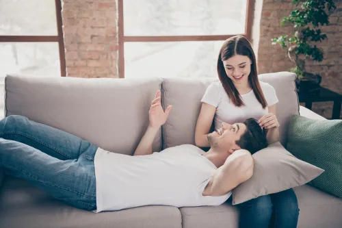   vīrietis guļ sievietē's lap on couch