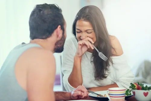   man och kvinna skrattar vid frukostbordet