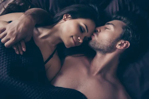   мъж целува жена's forehead in bed