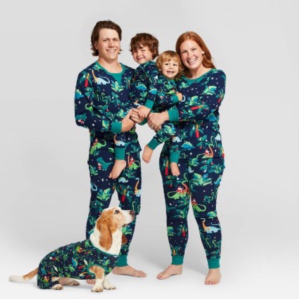 ayah dan ibu berkulit putih, dua anak, dan seekor anjing dengan piyama dinosaurus hijau
