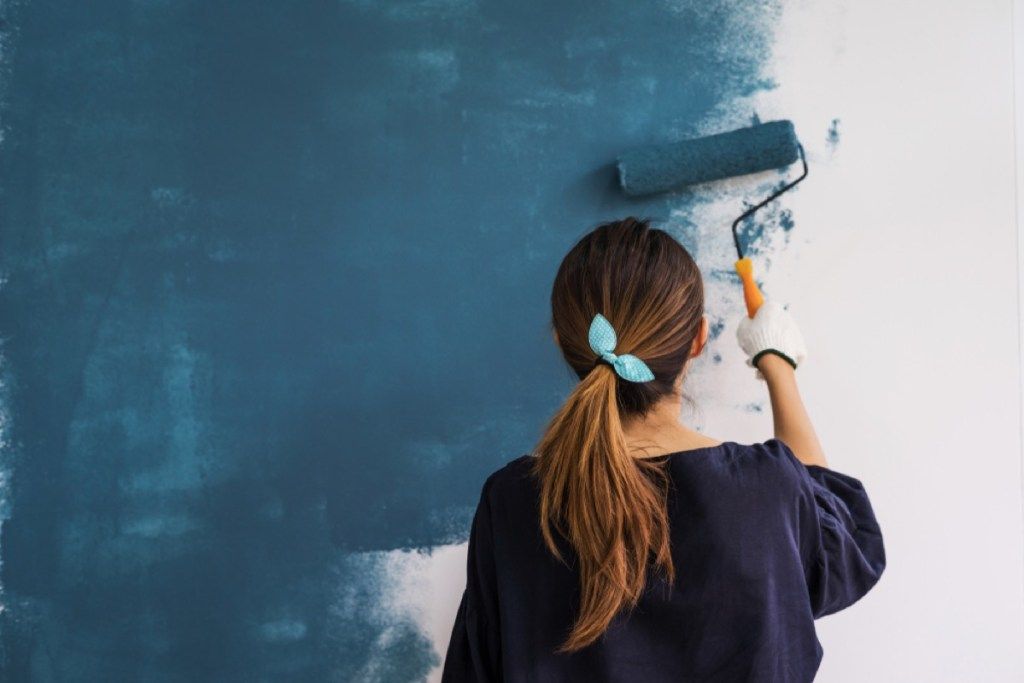 žena maľujúca steny modrou farbou