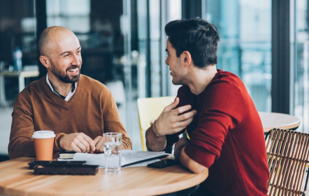 Två manliga vänner som talar och har en konversation i ett kafé
