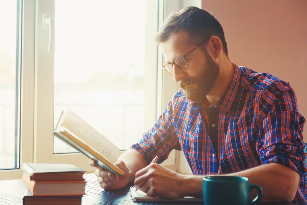 Muž čtení a studium u stolu