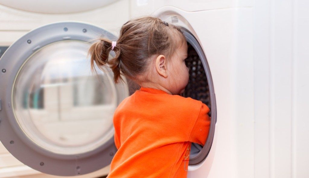 maža mergaitė, žiūrinti į skalbimo mašiną
