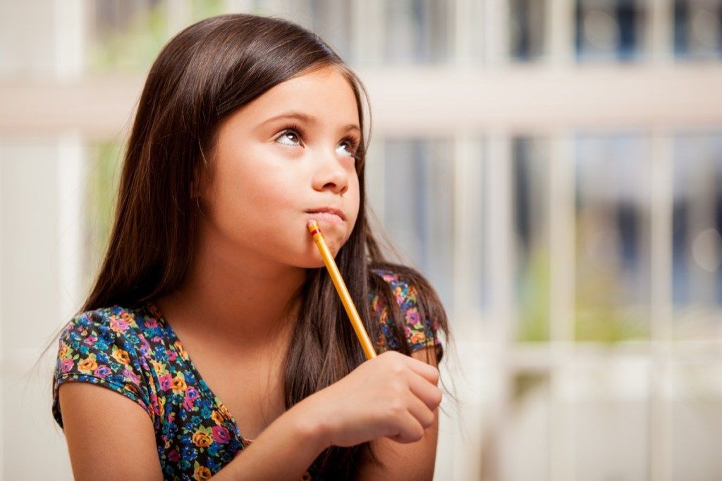 väike tüdruk, kes hoiab pliiatsit ja mõtleb