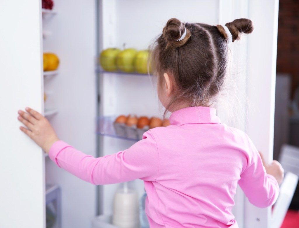 maža mergaitė atidaro šaldytuvą