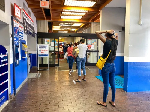   Emberek várakoznak sorban a floridai orlandói egyesült államokbeli postahivatalnál, ahol az emberek arcmaszkot viselnek, és távolságtartóak,