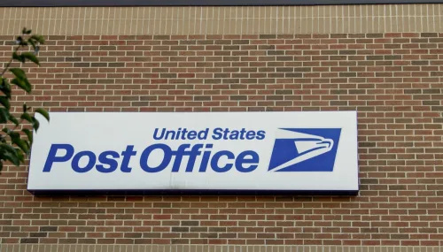   Vanjski izgled poštanskog ureda Sjedinjenih Američkih Država sa transparentom i logotipom.