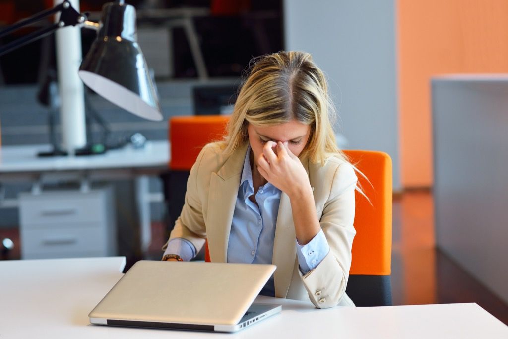 frustrert kvinne på kontoret foran den bærbare datamaskinen
