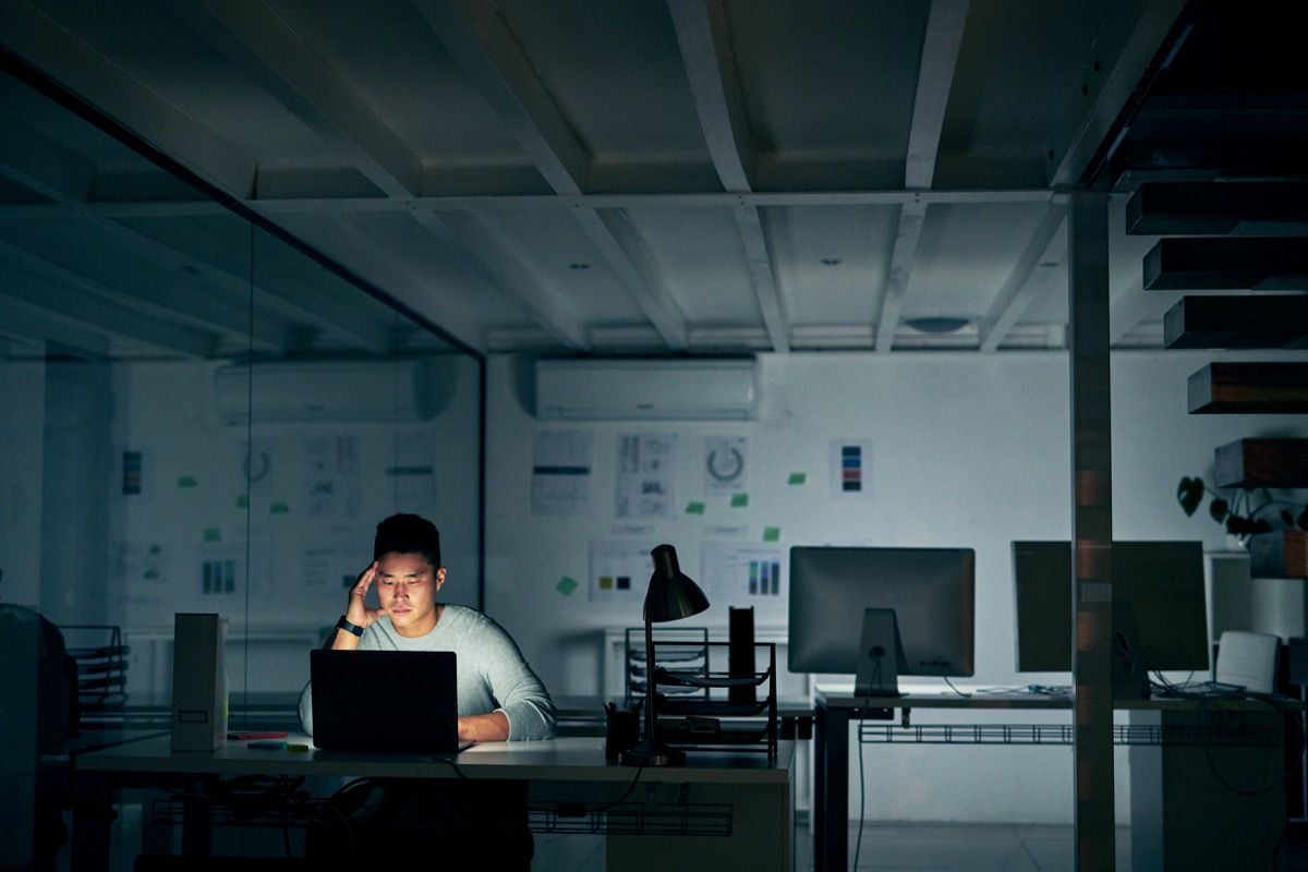 Pchnięcie młodego biznesmena patrząc zestresowany późną nocą w nowoczesnym biurze