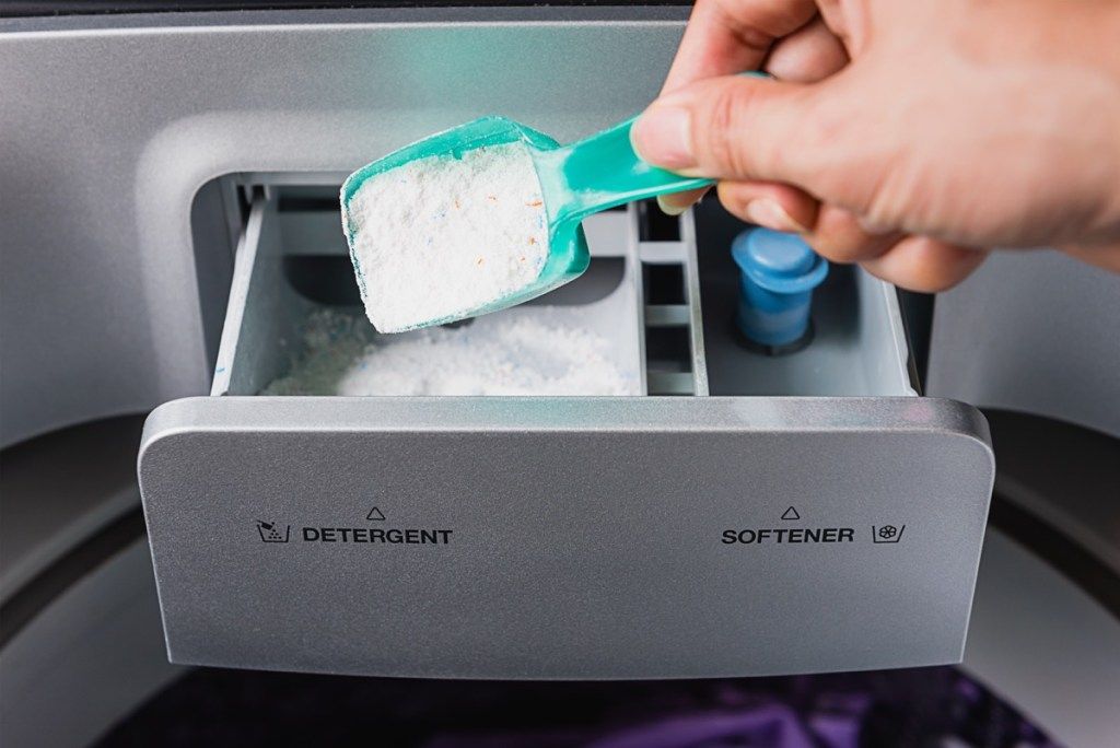 beyaz el çamaşır makinesine toz deterjan koyarak