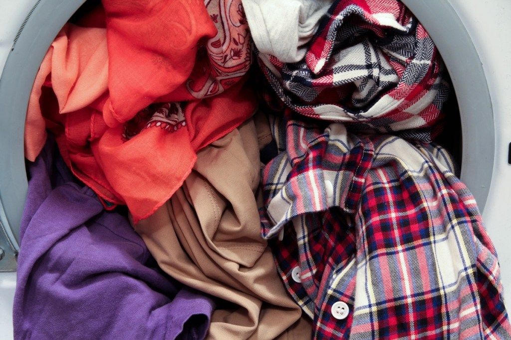 Přední plnění pračky přetížené barevnými špinavými oděvy, detailní pohled - Obrázek