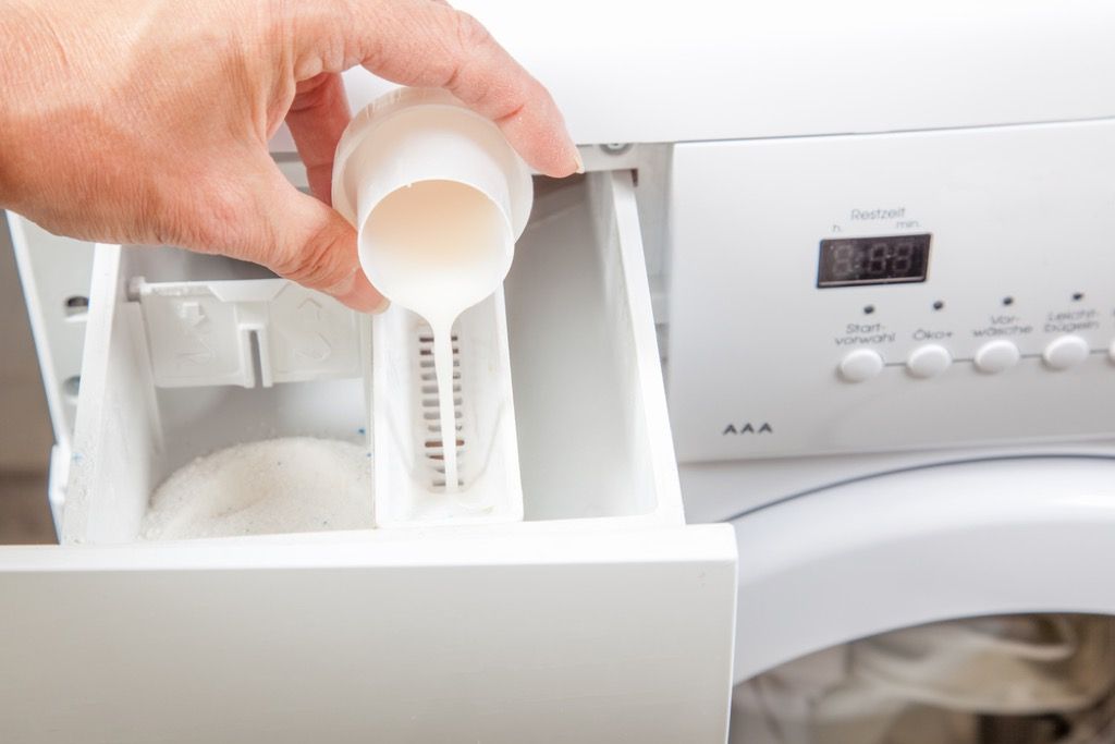 menuangkan bahan pencuci ke dalam mesin basuh