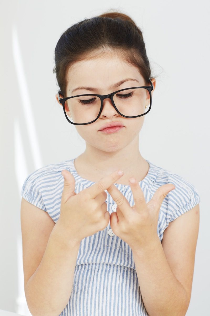 Maža mergaitė, skaičiuojanti ant pirštų, nešiojanti akinius