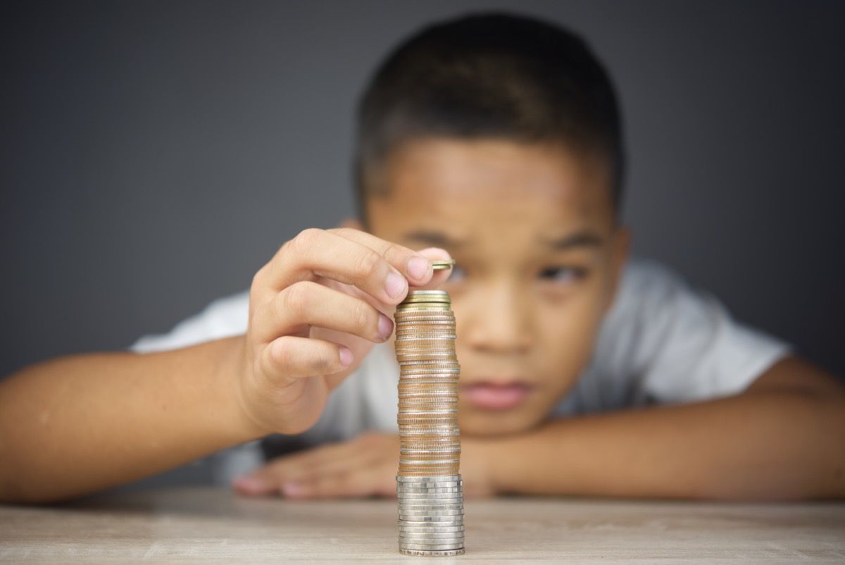 Jaunas berniukas, skaičiuojantis valiutos monetas