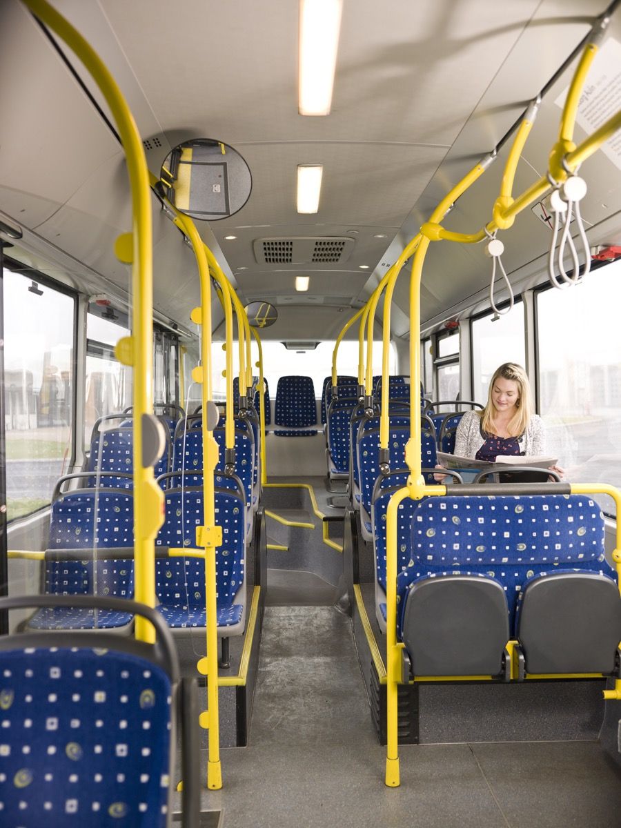 Nainen lukee paperia tyhjässä bussissa