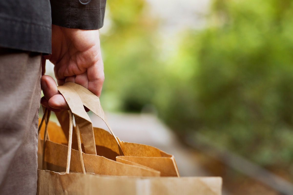vartotojų krepšelis, popierinių pirkinių maišelių uždarymas vyriškoje rankoje