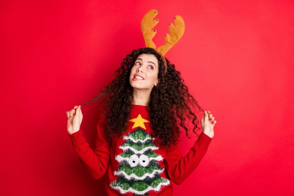 אישה צעירה בסוודר עץ חג המולד וקרניים איילים