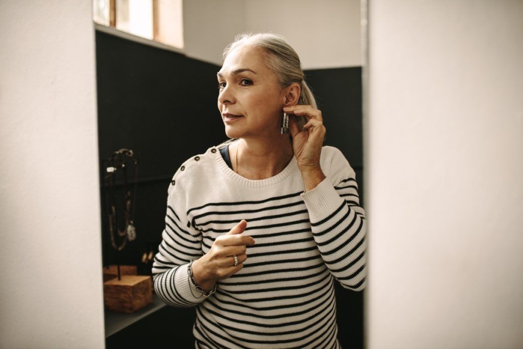 Mujer mayor con cabello blanco usa aretes, trucos de bricolaje