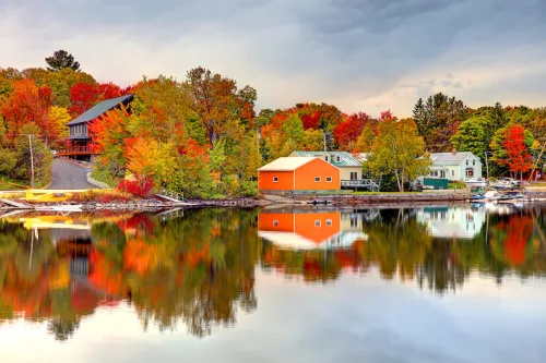   ग्रीनविल, मेन's Moosehead Lake surrounded by fall foliage.