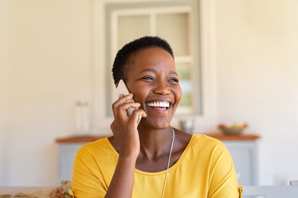 femeie râzând și sunând pe cineva la telefon
