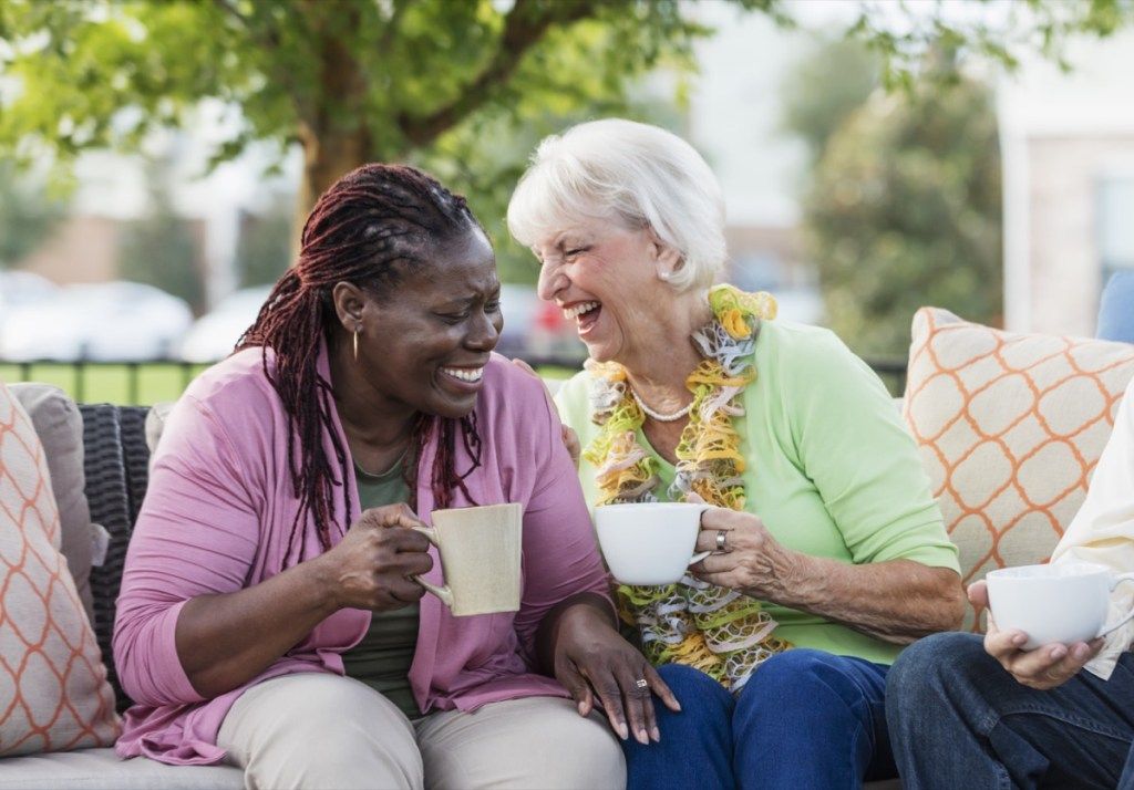 hai người bạn nữ lớn tuổi cười bên tách cà phê