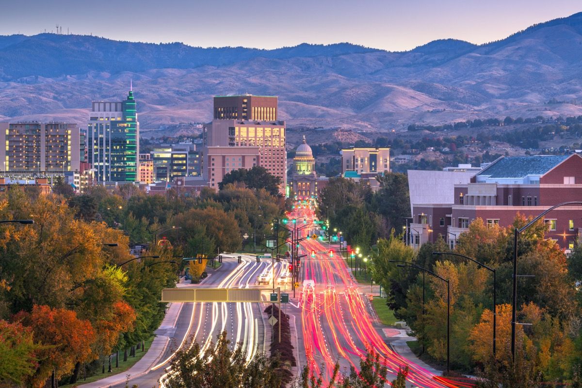 fotografie panorámy hôr, pohybujúce sa autá, budovy a štátny kapitol v Boise v štáte Idaho pri západe slnka