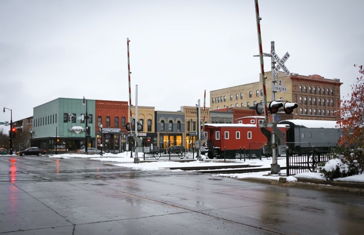 bybilledfoto af butik, jernbanespor og tog i centrum af Fargo, North Dakota i sneen