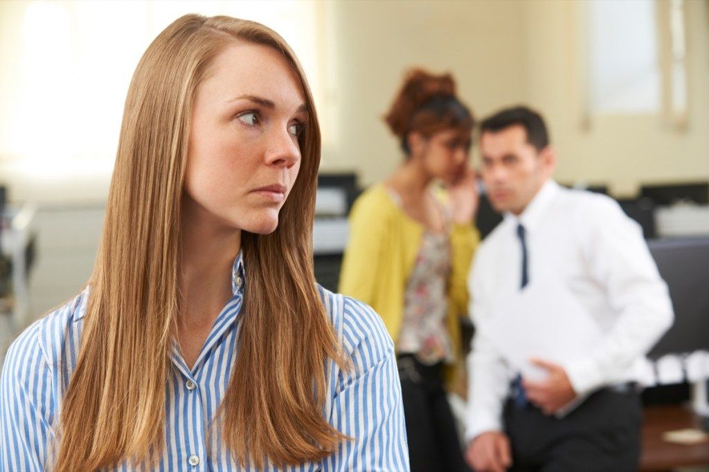 Forretningskvinde der bliver sladret af kollegaer i kontoret