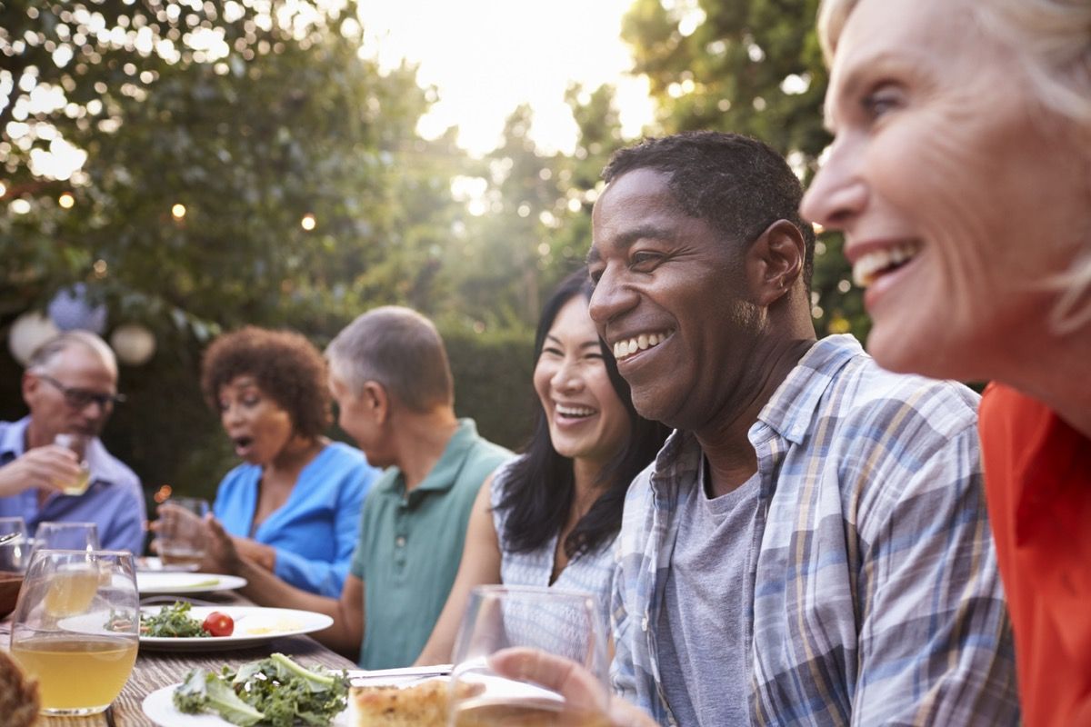 חברים בגיל העמידה אוכלים ארוחה בחוץ במהלך היום
