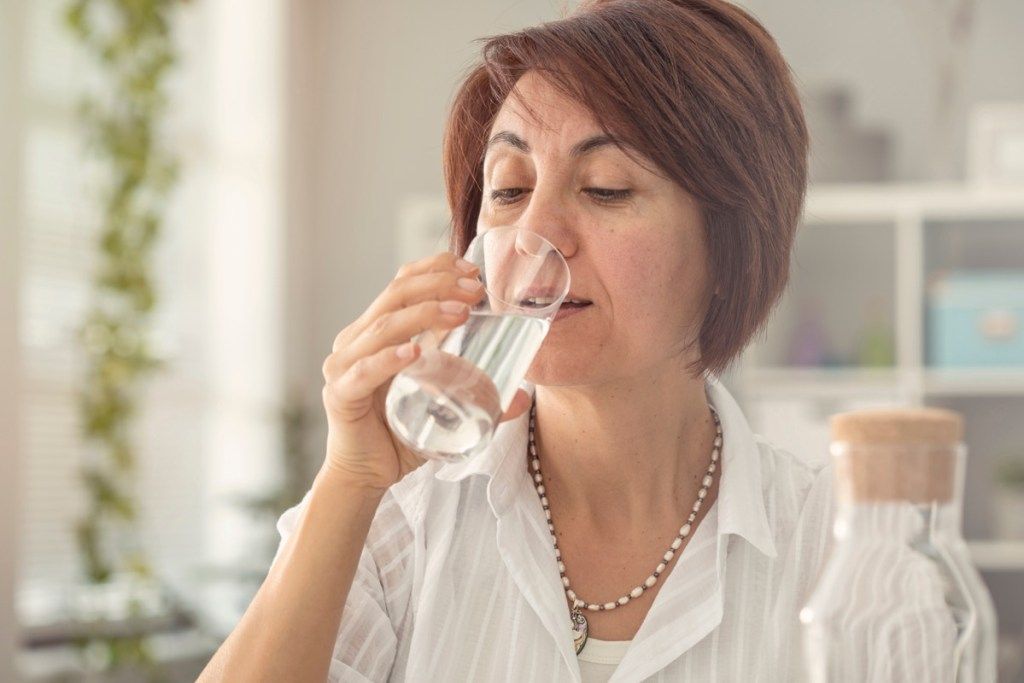 Idősebb nő iszik egy pohár vizet
