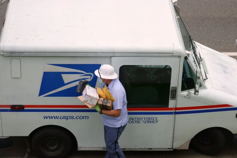   Пощенски превозвач, който носи кутии и пликове от пощенски камион