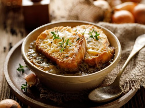   ซุปหัวหอมฝรั่งเศสแบบดั้งเดิมอบด้วยขนมปังกรอบชีสโรยด้วยโหระพาสดในระยะใกล้