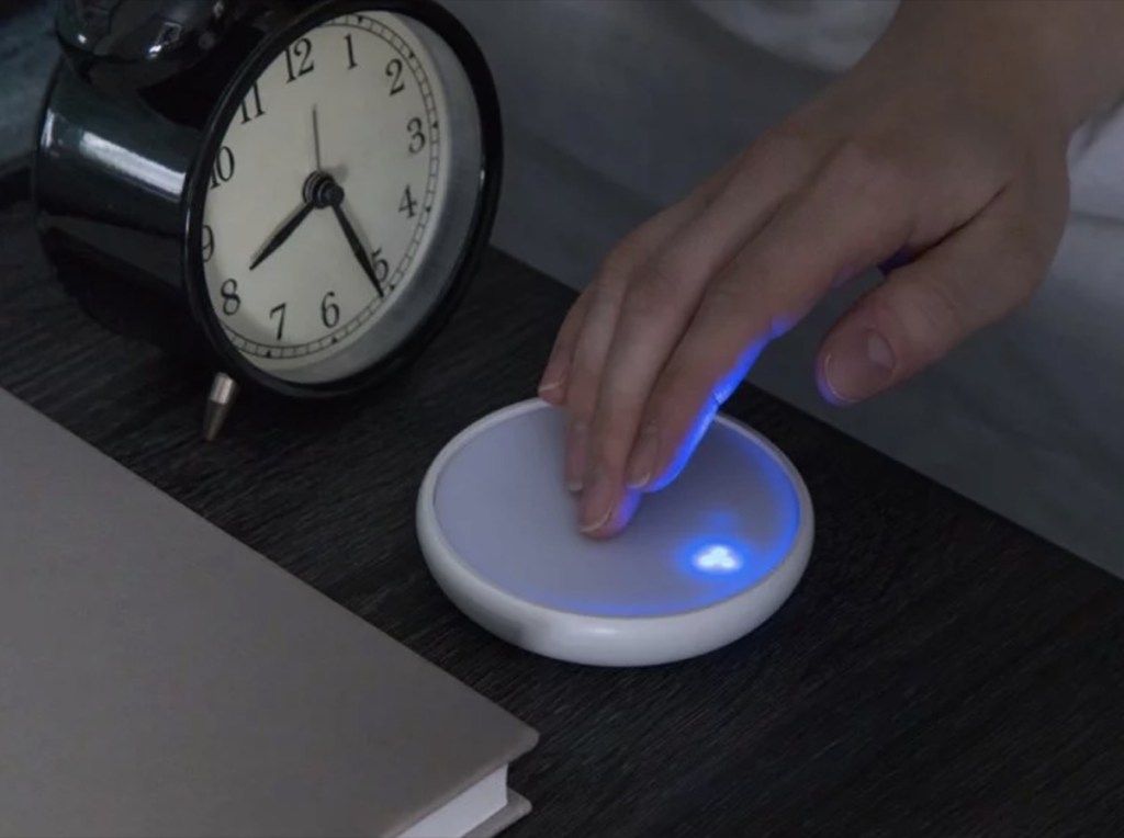 käsi koskettaa pyöreää laitetta pöydällä analogisella herätyskellolla, paremmat unen välttämättömyydet