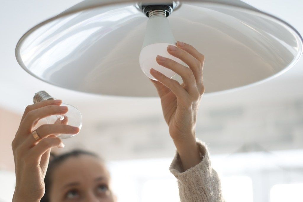 kvinna installerar vit glödlampa i hem saker i ditt hus lockar skadedjur
