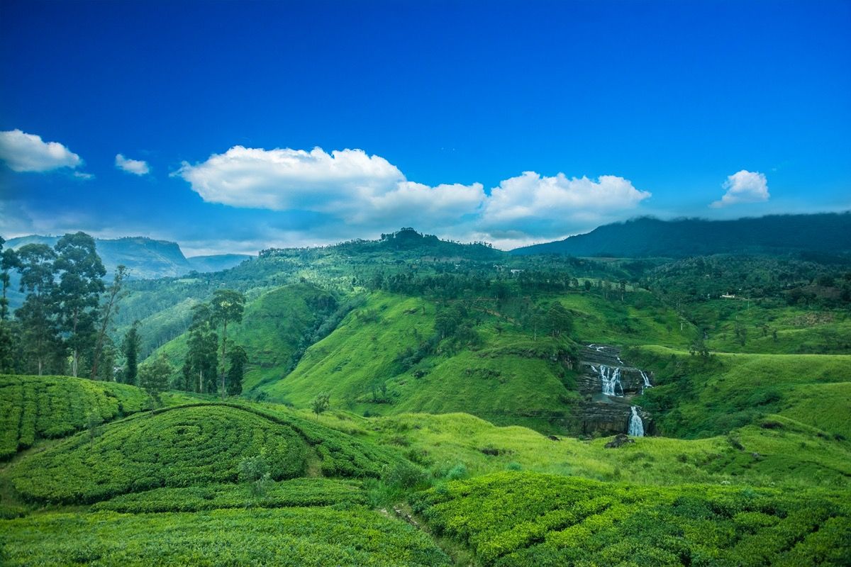 grønn dal, fossefall og blå himmel i Sri Lanka