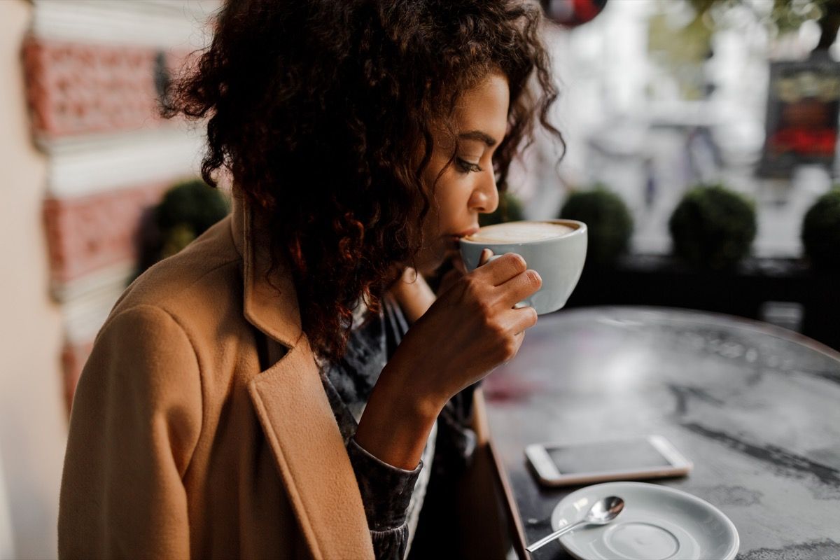 Svart kvinne som drikker en latte på en kaffebar om vinteren