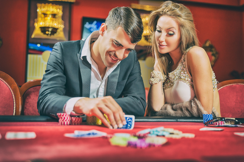   Un hombre jugando al póquer junto a su pareja en un casino.