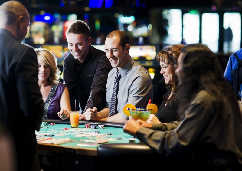   Un grupo de personas bebiendo en una mesa de cartas en un casino.