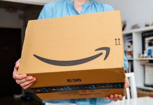ПАРИЖ, ФРАНЦИЯ - 4 ЮЛИ 2018 г .: Жена, получила пакет Amazon Prime, доставена, подготвяща се за разопаковане, горд клиент на Amazon Prime с библиотека във фонов режим