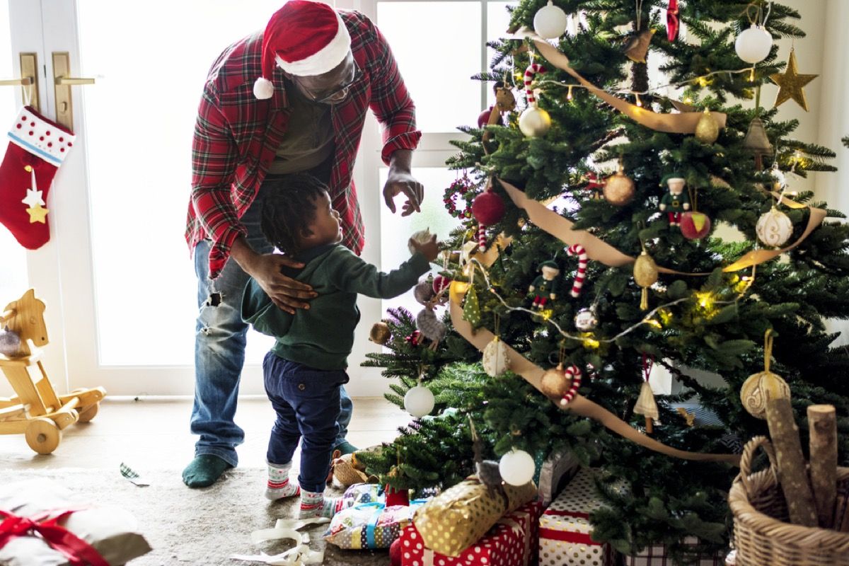 क्रिसमस ट्री को सजाते युवा काले पिता और बच्चा बेटा
