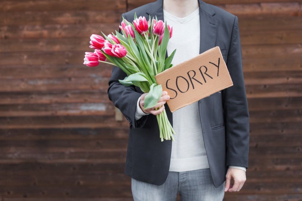 người đàn ông cầm hoa và ký tên xin lỗi