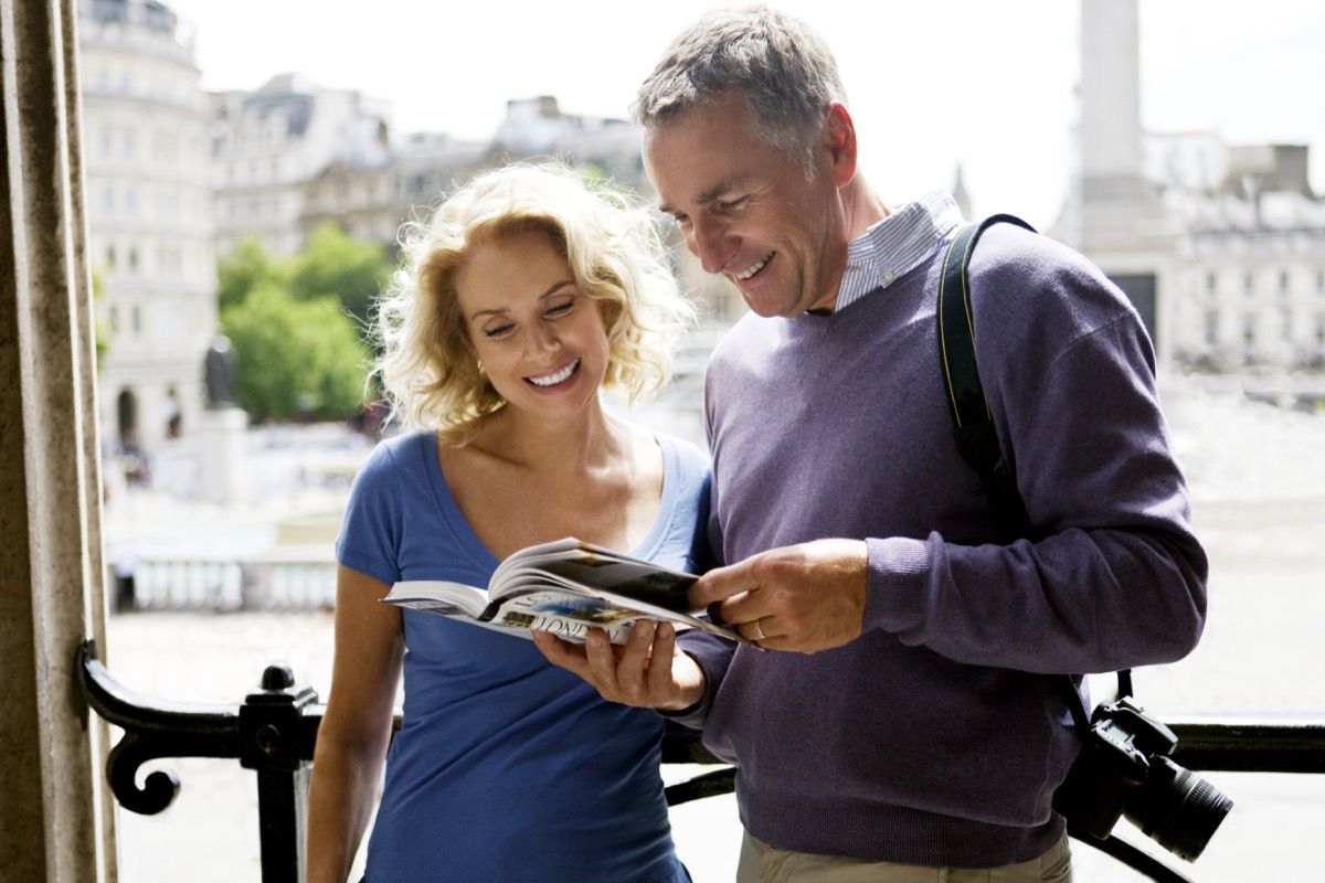 Turistički par koji čita knjigu o znamenitostima Londona prije razgledavanja