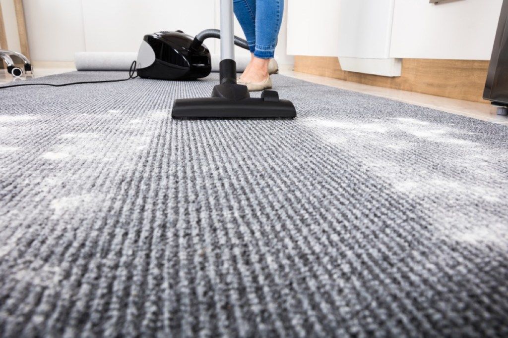 mujer aspirando el polvo de la alfombra, consejos sencillos para el hogar