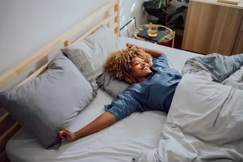   نوجوان سیاہ فام عورت بستر میں دن میں خواب دیکھ رہی ہے۔