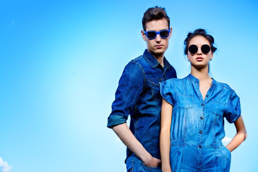 vyras ir moteris, vilkintys mėlynus džinsinio audinio rūbus mėlyname fone - spalvoti faktai